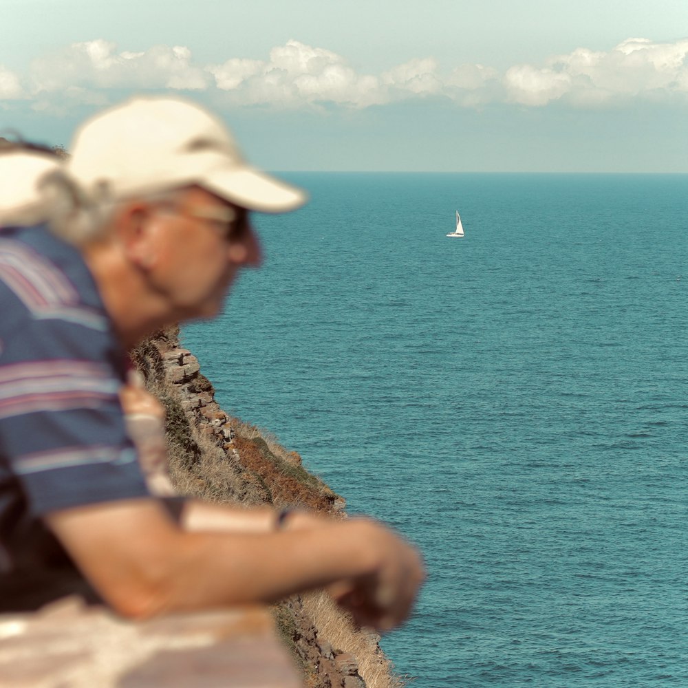 a man sitting on a ledge overlooking a body of water