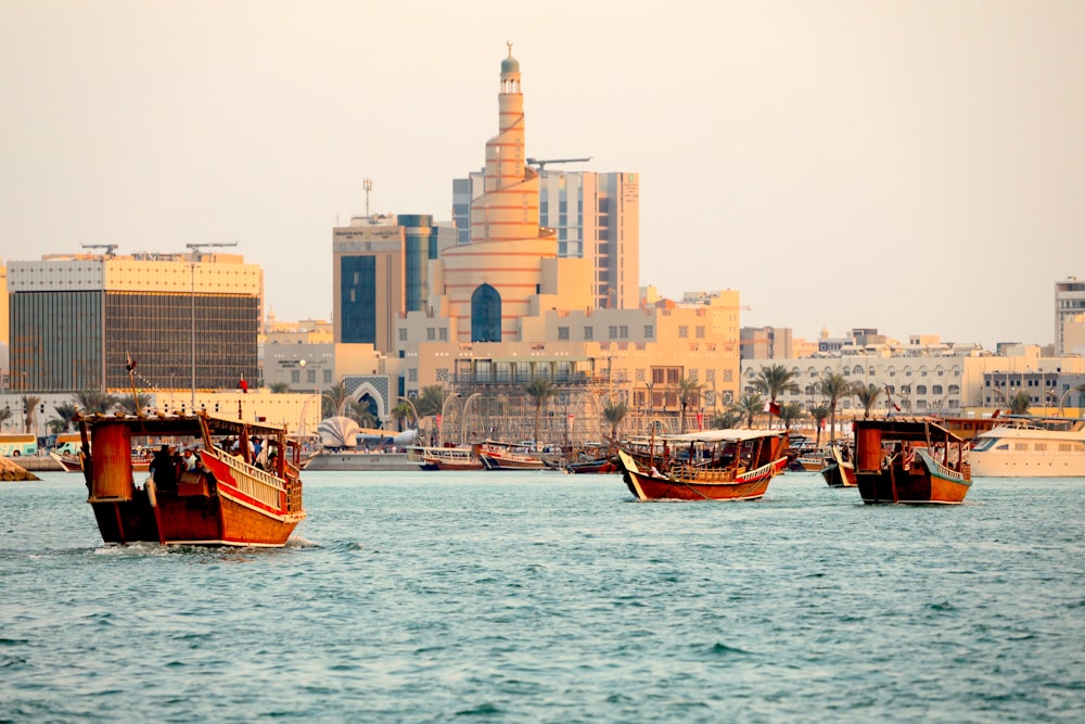 a group of boats in a body of water with buildings in the background