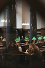 a couple of people sitting at a table with green lamps