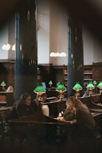 a couple of people sitting at a table with green lamps