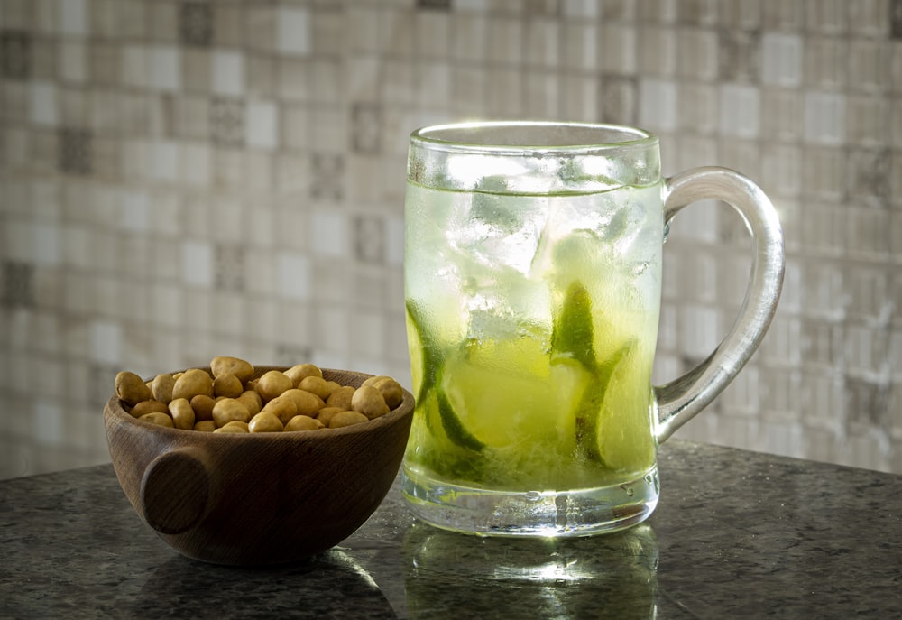 a glass of tea with a green drink and nuts in it