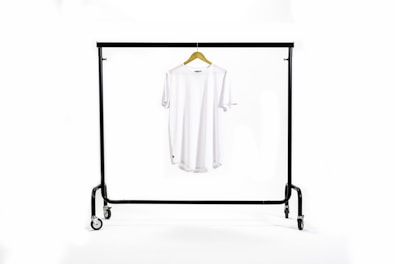 Minimalist t-shirt displayed on a hanger against a clean white wall.