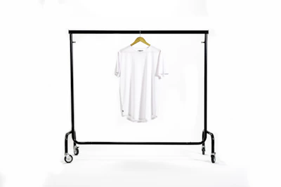 Close-up of a clean, minimalist black oversized hoodie on a hanger against a white wall.