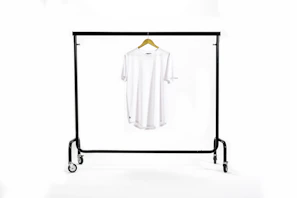 Black t-shirt hanging on a minimalist metal rack with a blurred urban background