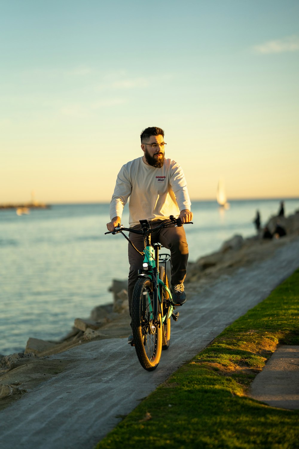 um homem andando de bicicleta em um caminho à beira da água