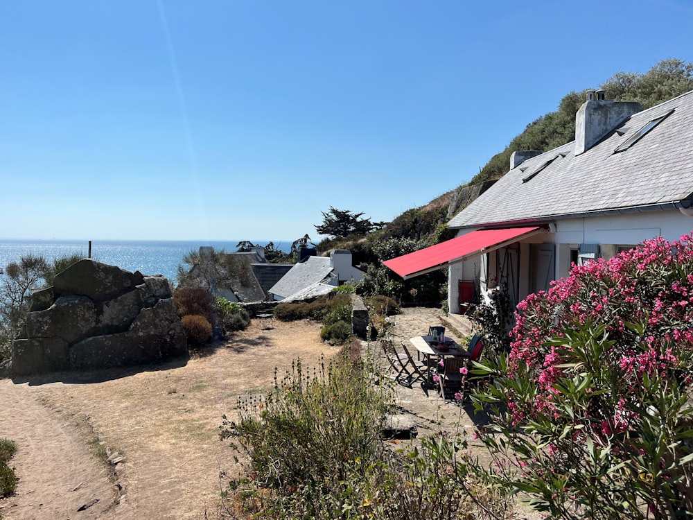 a house with a rocky beach and a body of water in the background