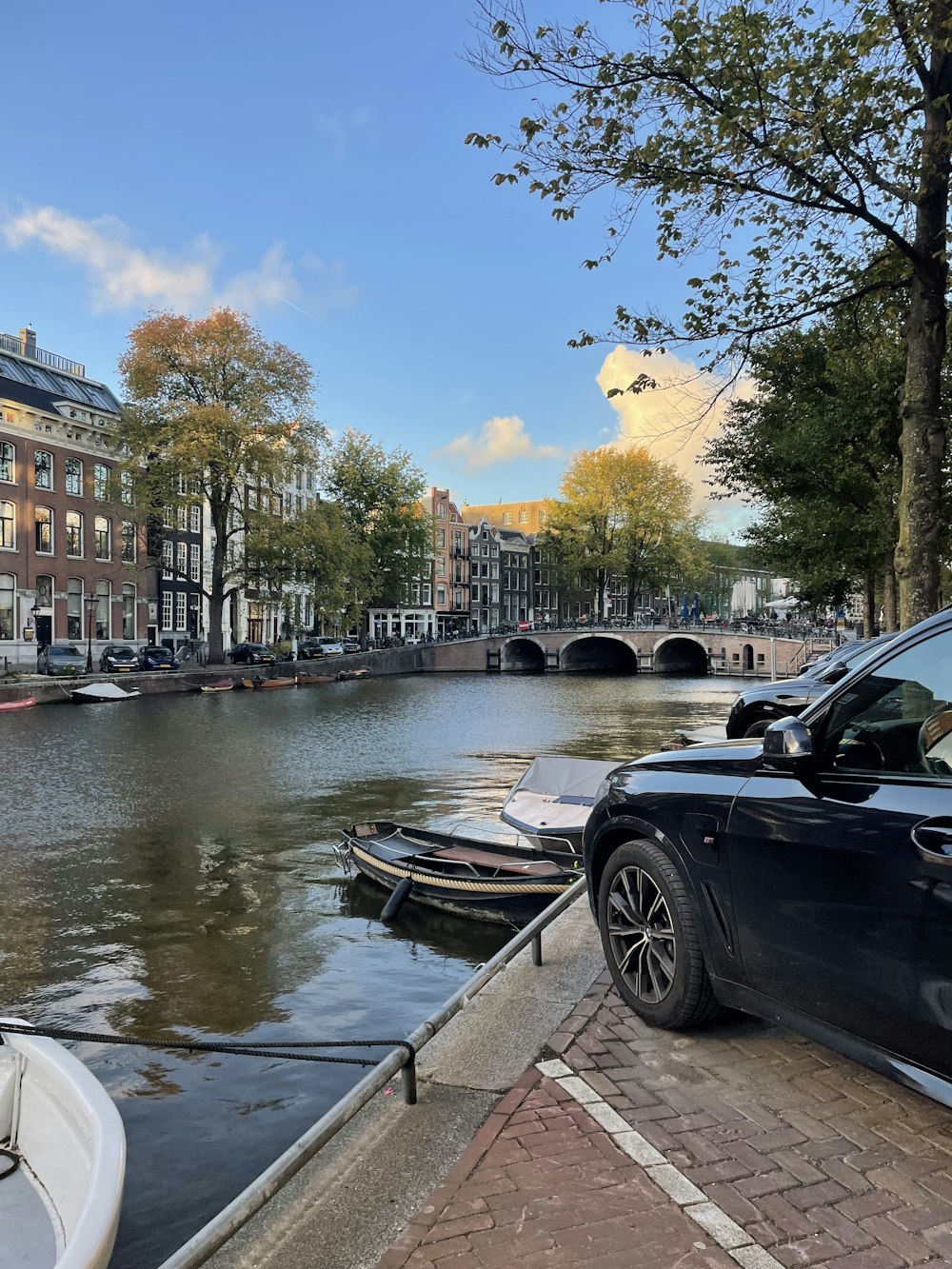a car parked on a brick walkway next to a river with boats