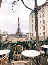 A softly lit close-up of Parisian café tables arranged outside on a quiet street at dusk.