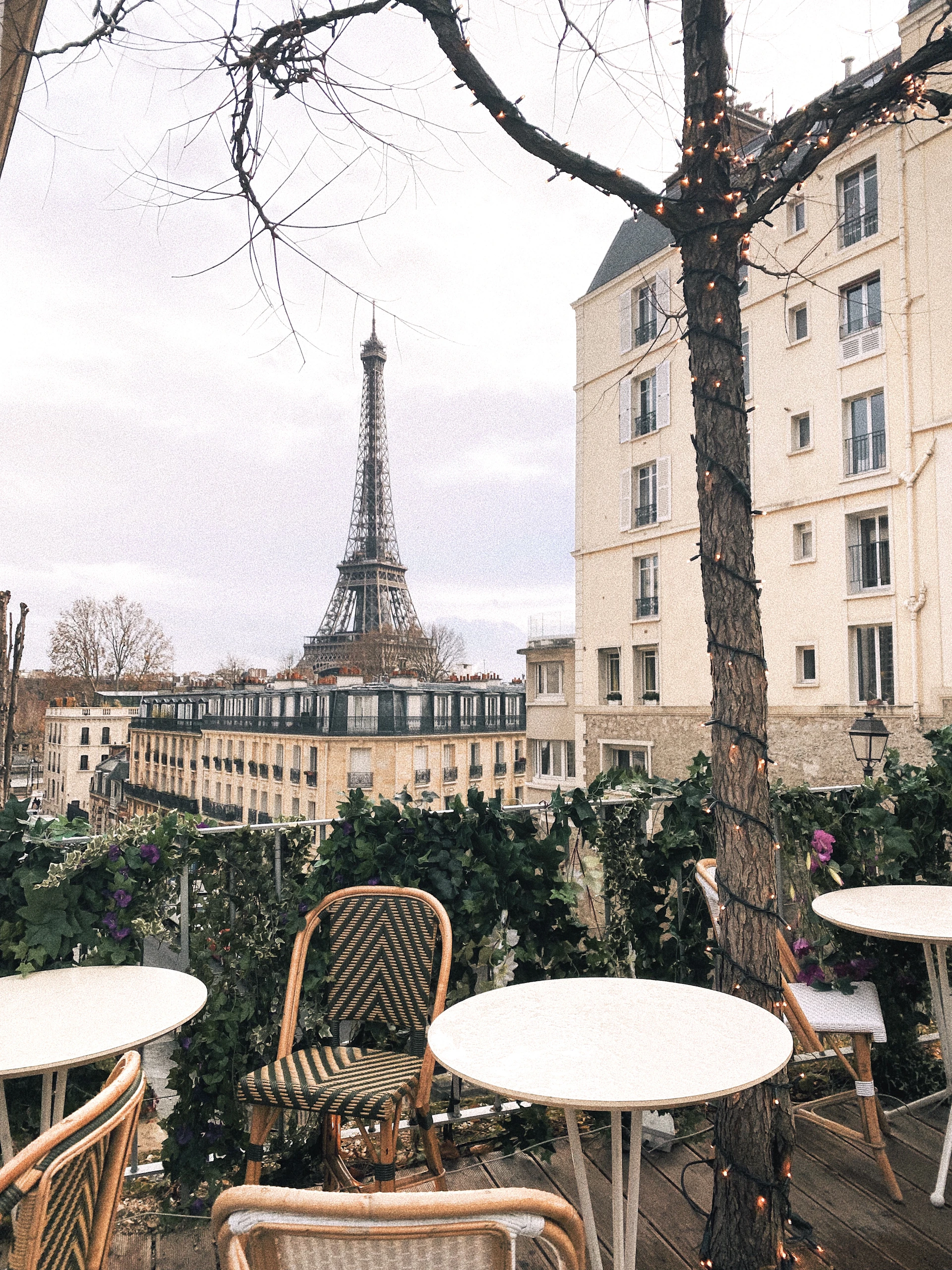 A charming street café in Paris bathed in warm afternoon light, with colorful chairs and a glimpse of the Eiffel Tower in the background.