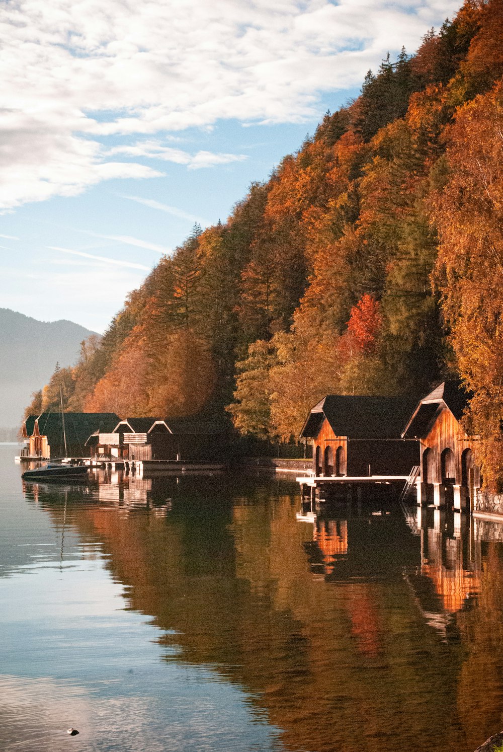 a house on a dock by a lake with trees and mountains in the background