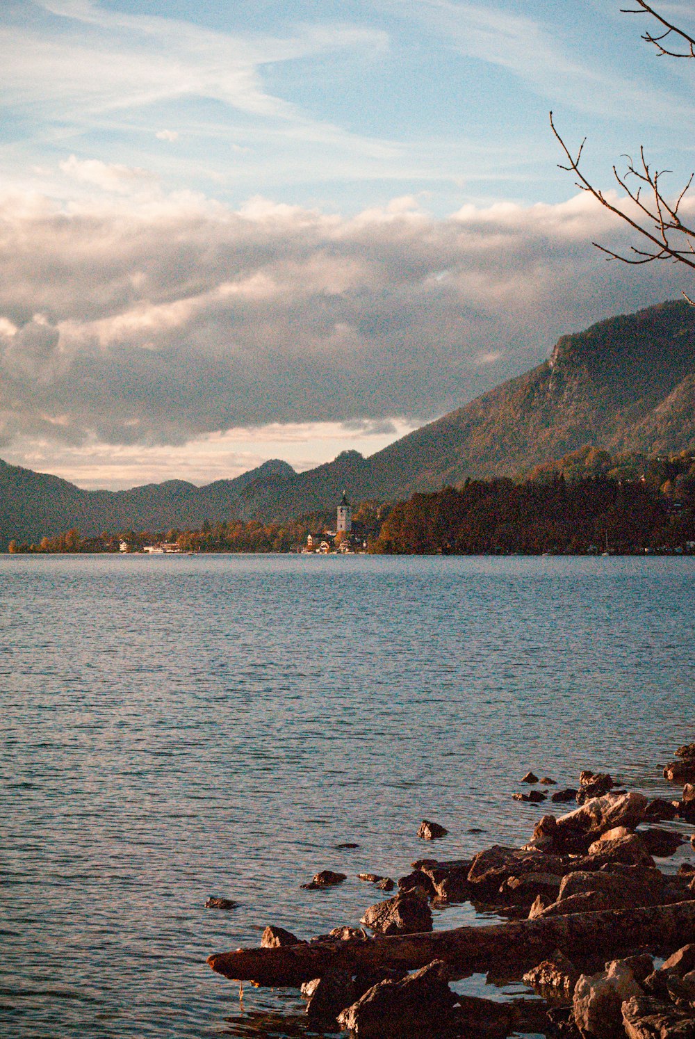 a body of water with a rocky shore and mountains in the background