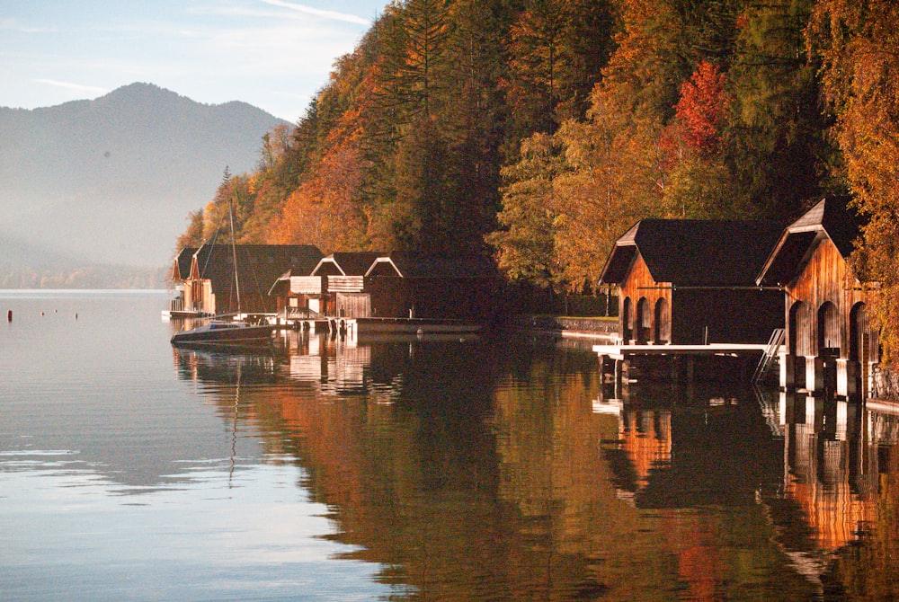 a house on a dock by a lake with trees and mountains in the background
