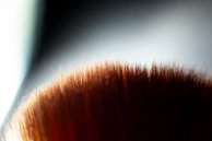 Artistic shot of soft makeup brushes and powder textures blending seamlessly into a taupe rose gradient background.