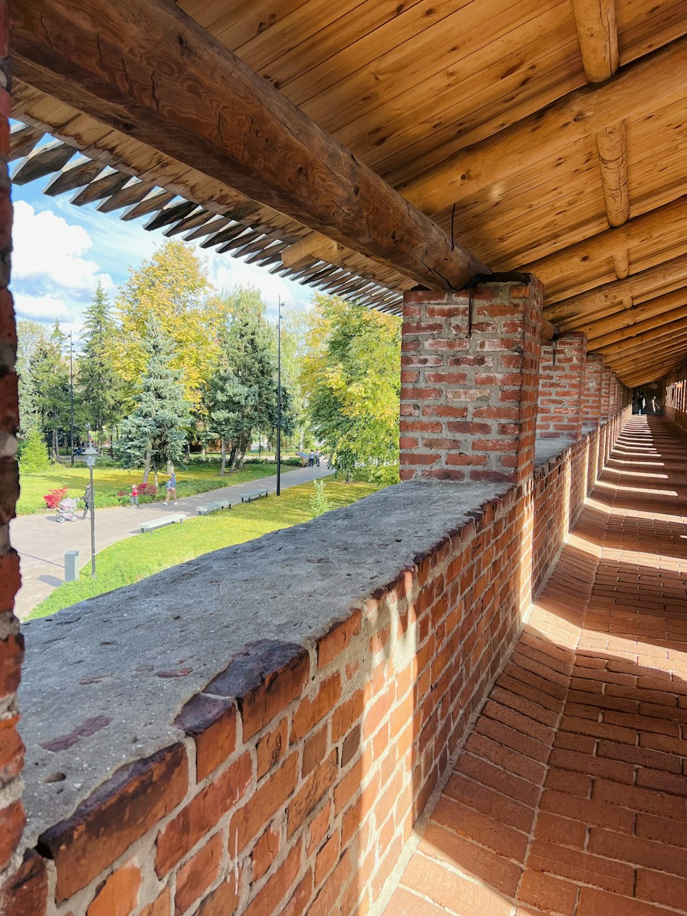 a brick wall with a brick walkway and trees in the background