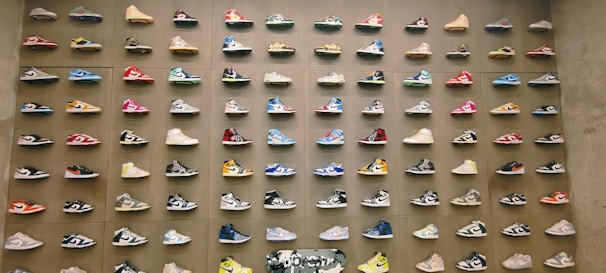 Brightly colored sneakers and casual shoes displayed against a bold, abstract painted backdrop