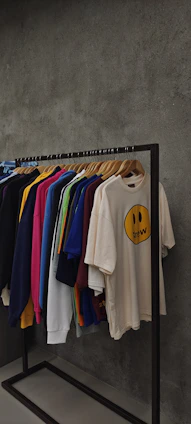 A vibrant display of custom printed t-shirts and hoodies hanging on a rack in a cozy studio.