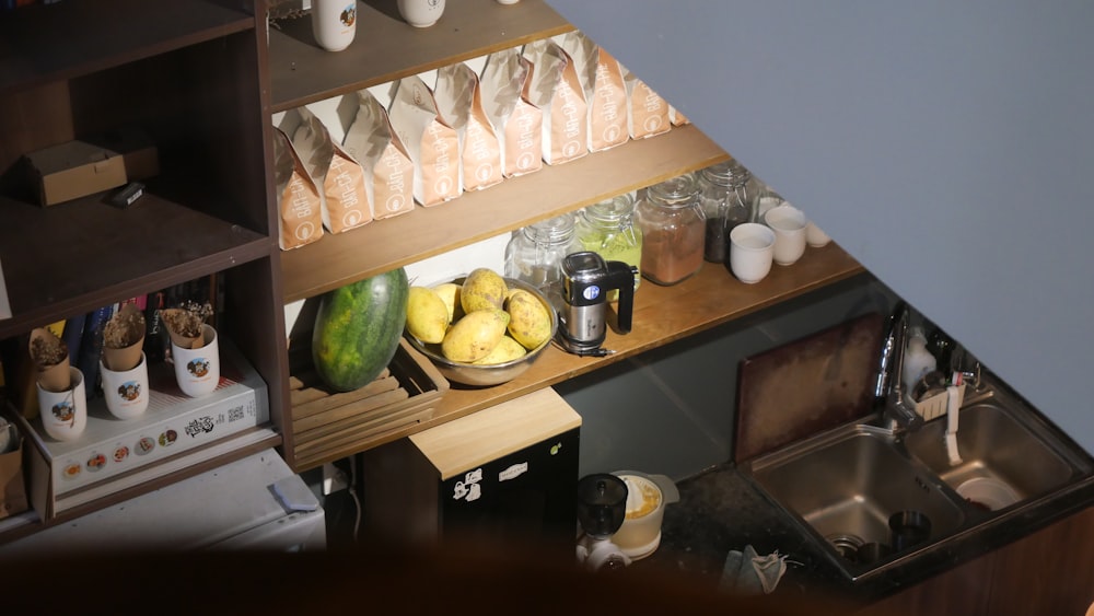 a kitchen counter with a sink and a shelf with food on it