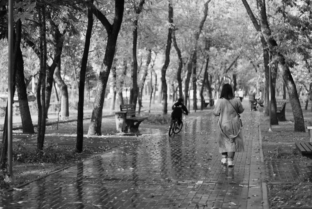 a person walking on a path with a child riding a bicycle