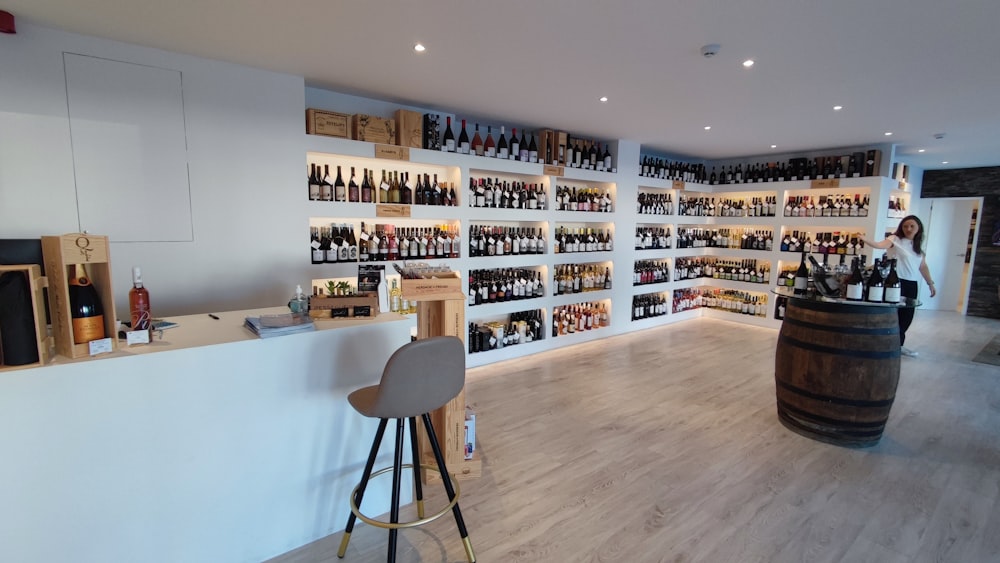 a person standing in a room with a bar and wine bottles