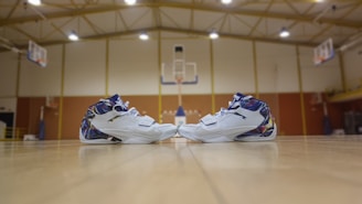 A pair of sleek basketball shoes on a wooden court floor.