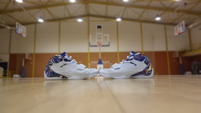 A pair of sleek basketball shoes on a wooden court floor.