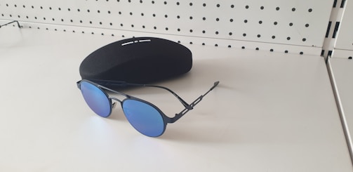 A man adjusting stylish blue light glasses in front of a minimalist white background.