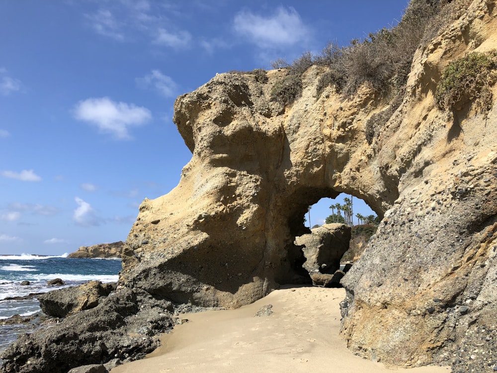 a large rock arch over a beach