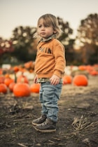a child standing in front of pumpkins