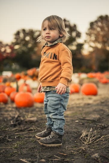 a child standing in front of pumpkins