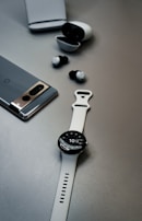 A minimalist setup featuring headphones, smartphone, and a notebook on a gray surface