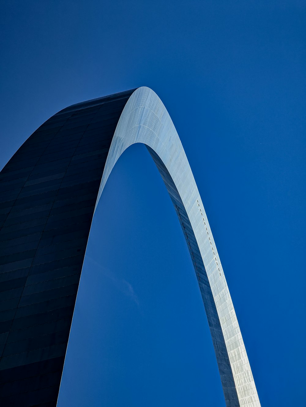 a tall bridge with a blue sky with Gateway Arch in the background