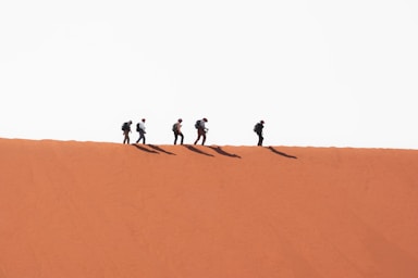 balance and symmetry for photo composition,how to photograph people walking on a dune; a group of people walking on sand