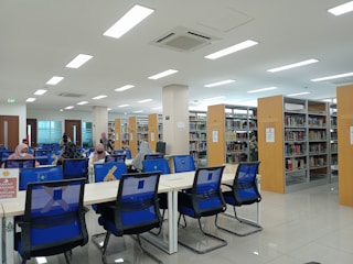 A spacious library corner with students quietly reading books at well-lit desks.