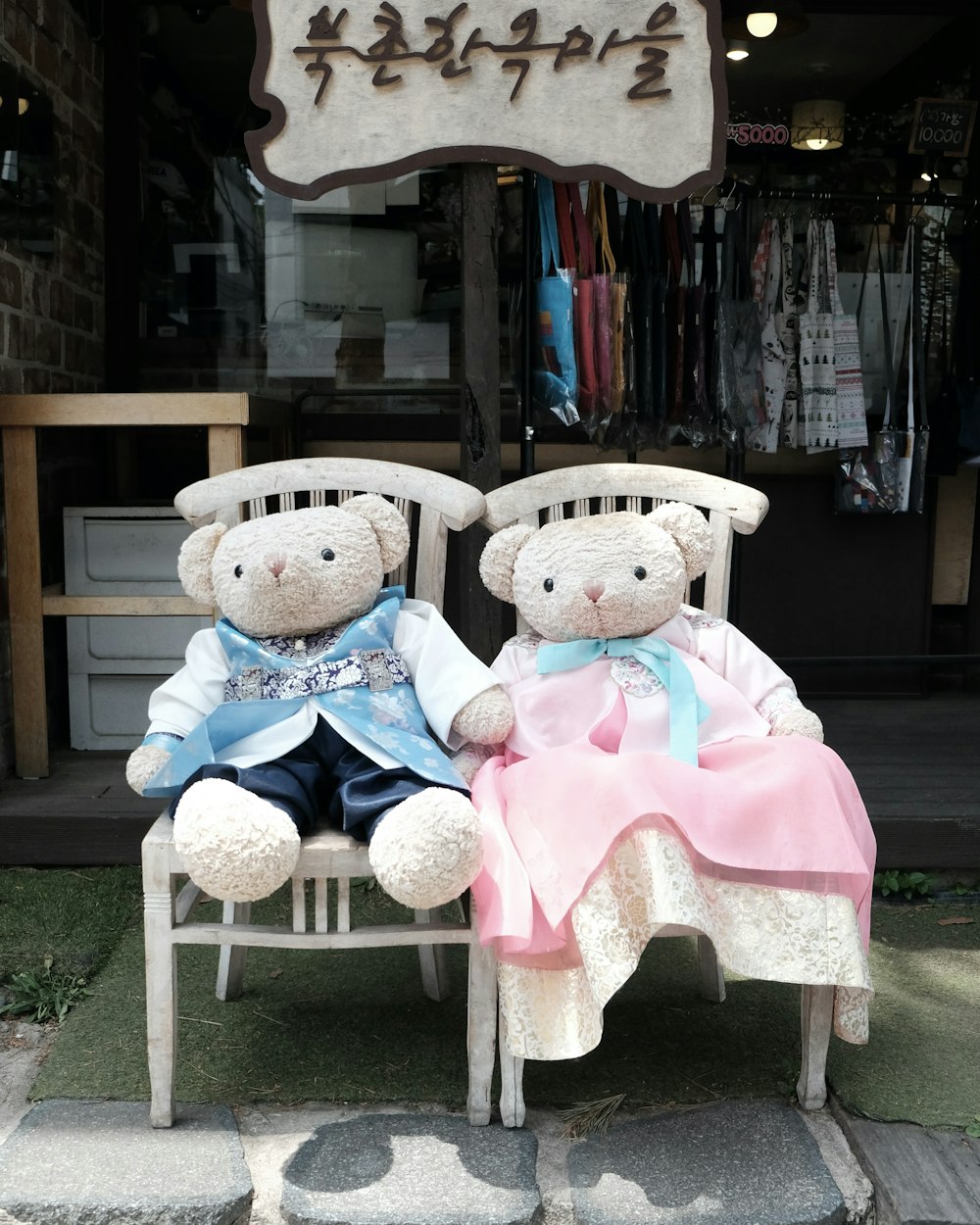 a couple of teddy bears sit on a bench