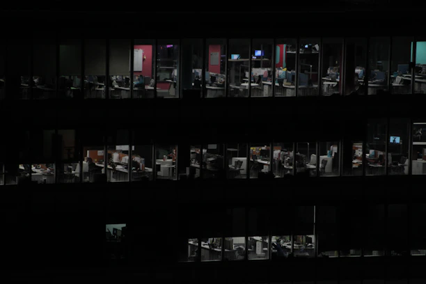 A dedicated team working late at night in a modern office with blue and black tones.