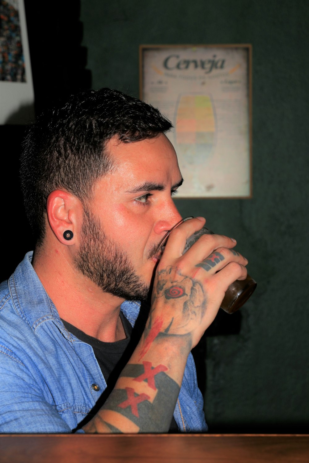 a man with tattoos drinking from a glass