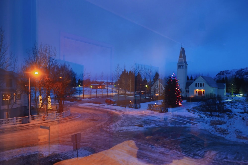 a snowy street with trees and buildings