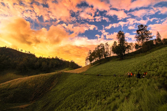 A vibrant sunset over a group of happy travelers exploring a scenic mountain trail.