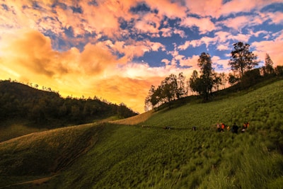 A vibrant group of travelers enjoying a sunset hike in the hills, bathed in warm orange and yellow light.