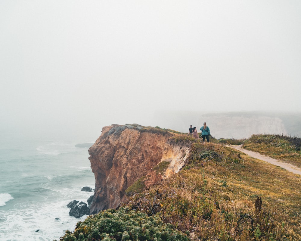 a group of people on a cliff by the ocean