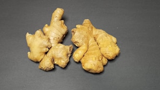 Fresh ginger roots and finely ground ginger powder artfully arranged on a rustic kitchen surface.
