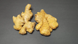 Close-up of dried ginger roots arranged on a rustic wooden table with soft natural light.