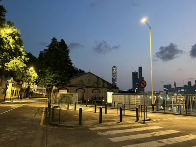 A peaceful city street at dusk, glowing softly under vintage street lamps.