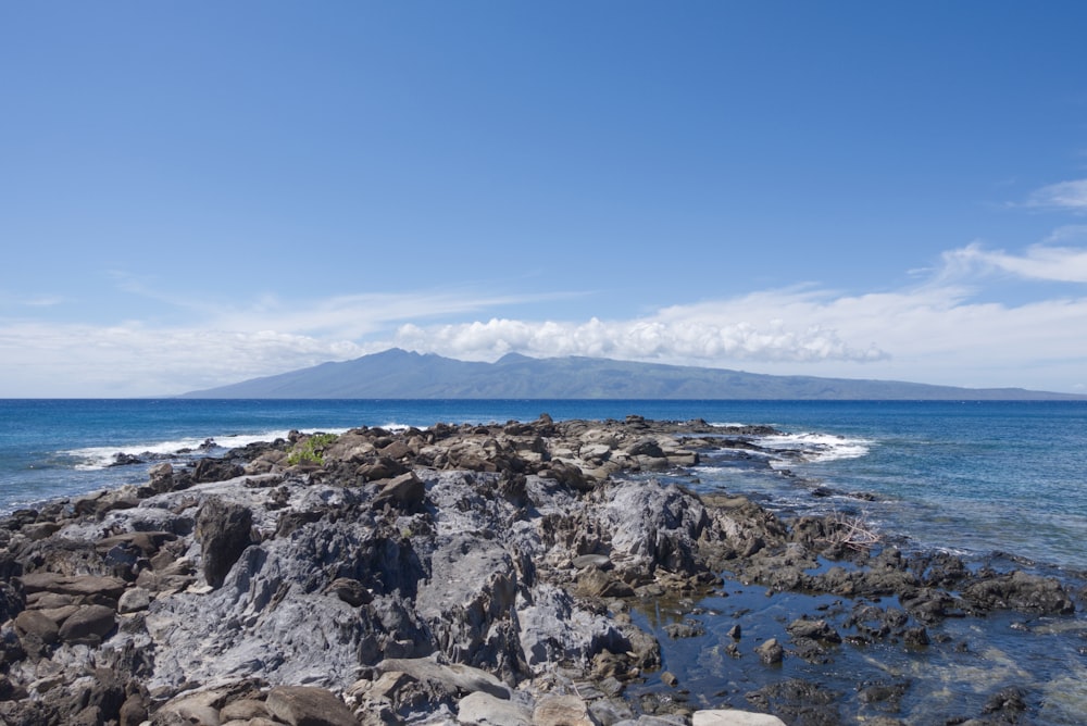 a rocky beach with a body of water in the background