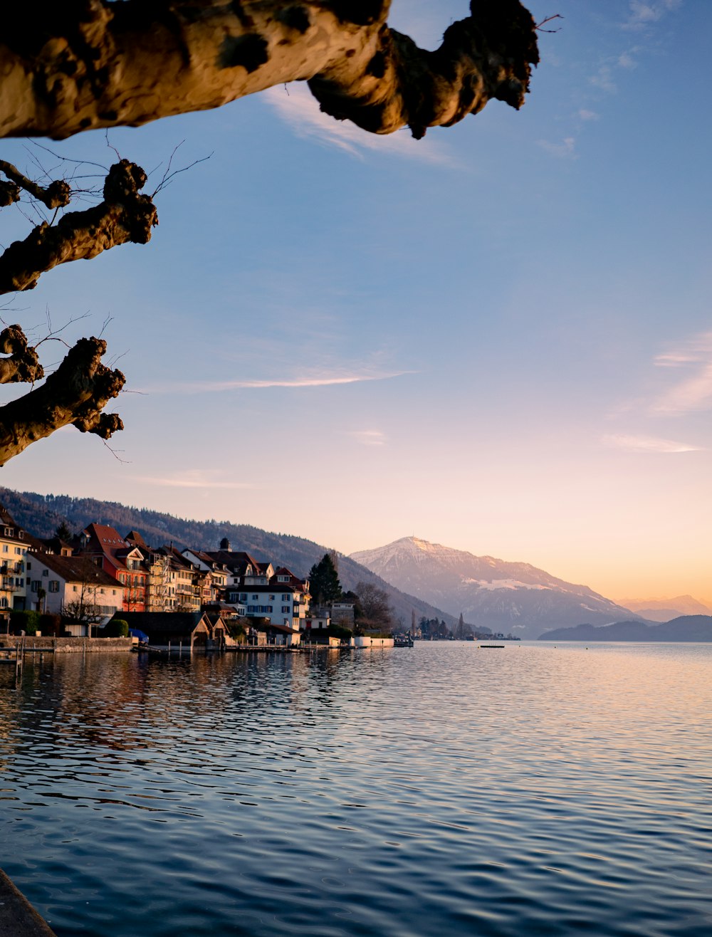 a body of water with buildings and mountains in the background