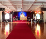 Large hall set up with chairs and mats for group spiritual gatherings.