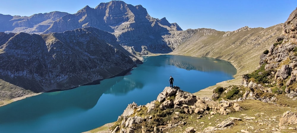 a person standing on a rock near a lake