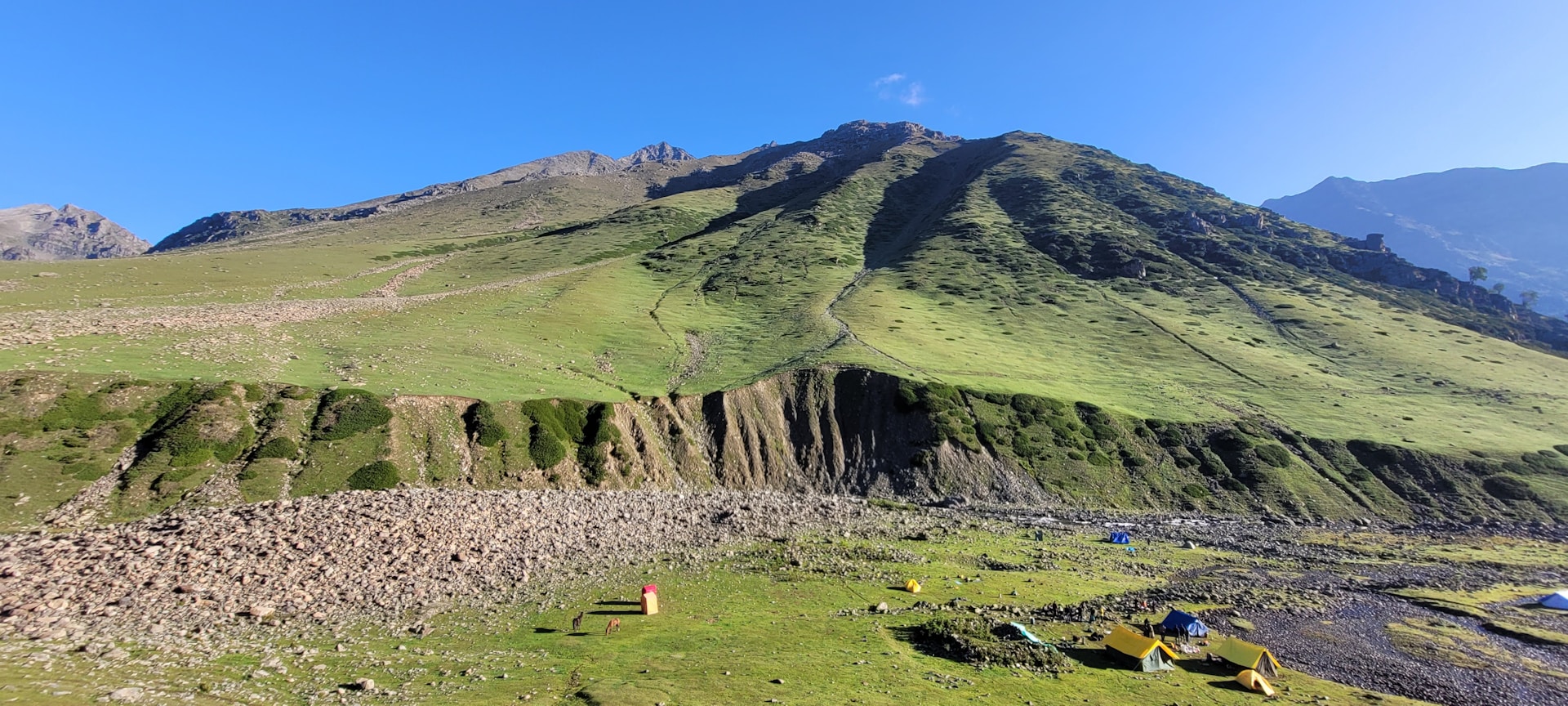 a grassy valley with a stone wall
