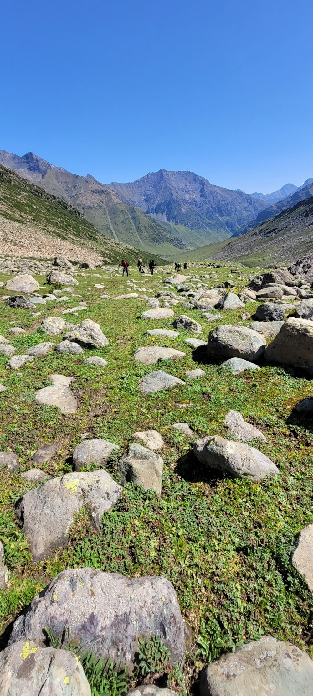 a group of people walking on a rocky path in a valley