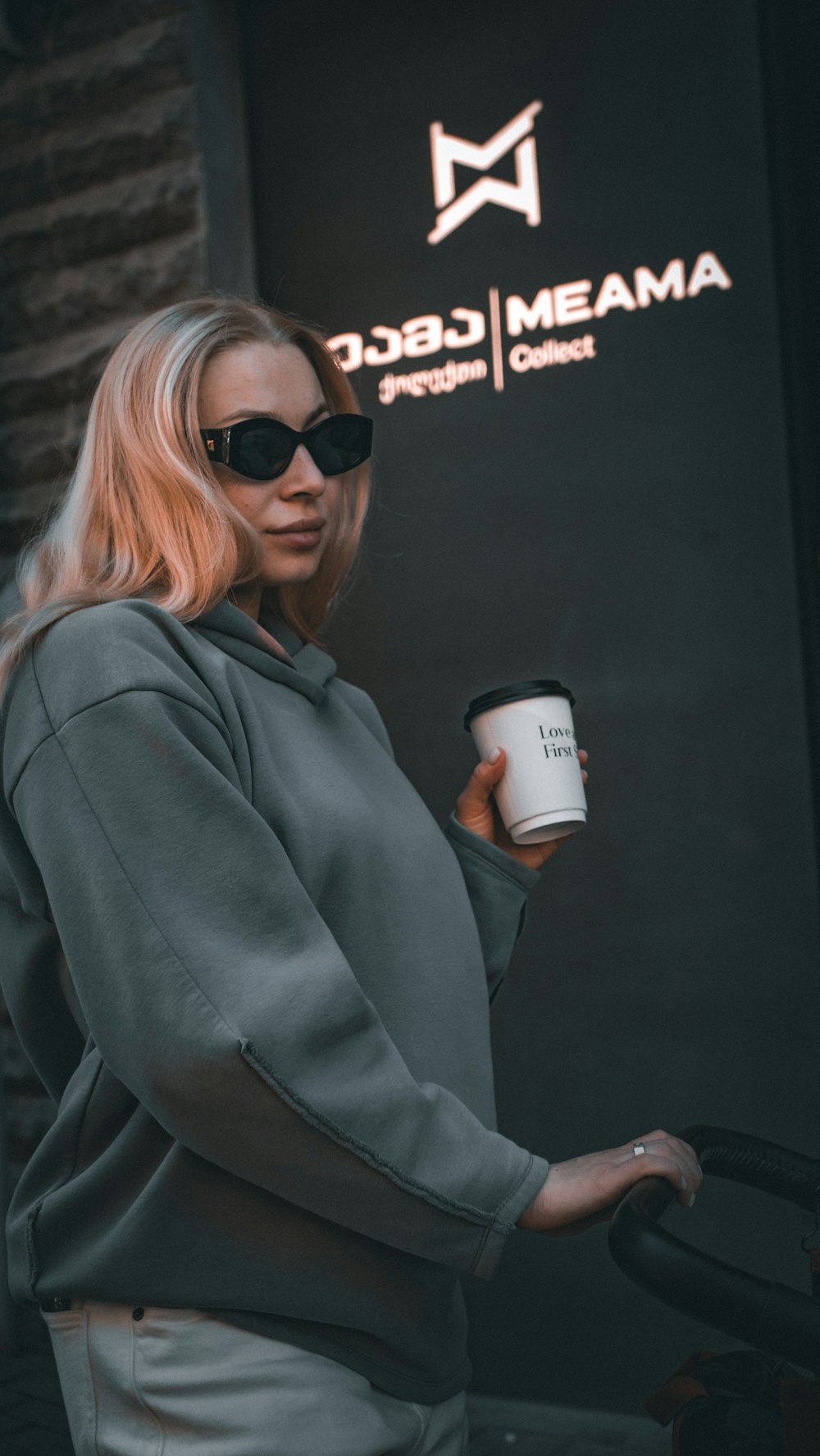 a person wearing sunglasses and holding a coffee cup